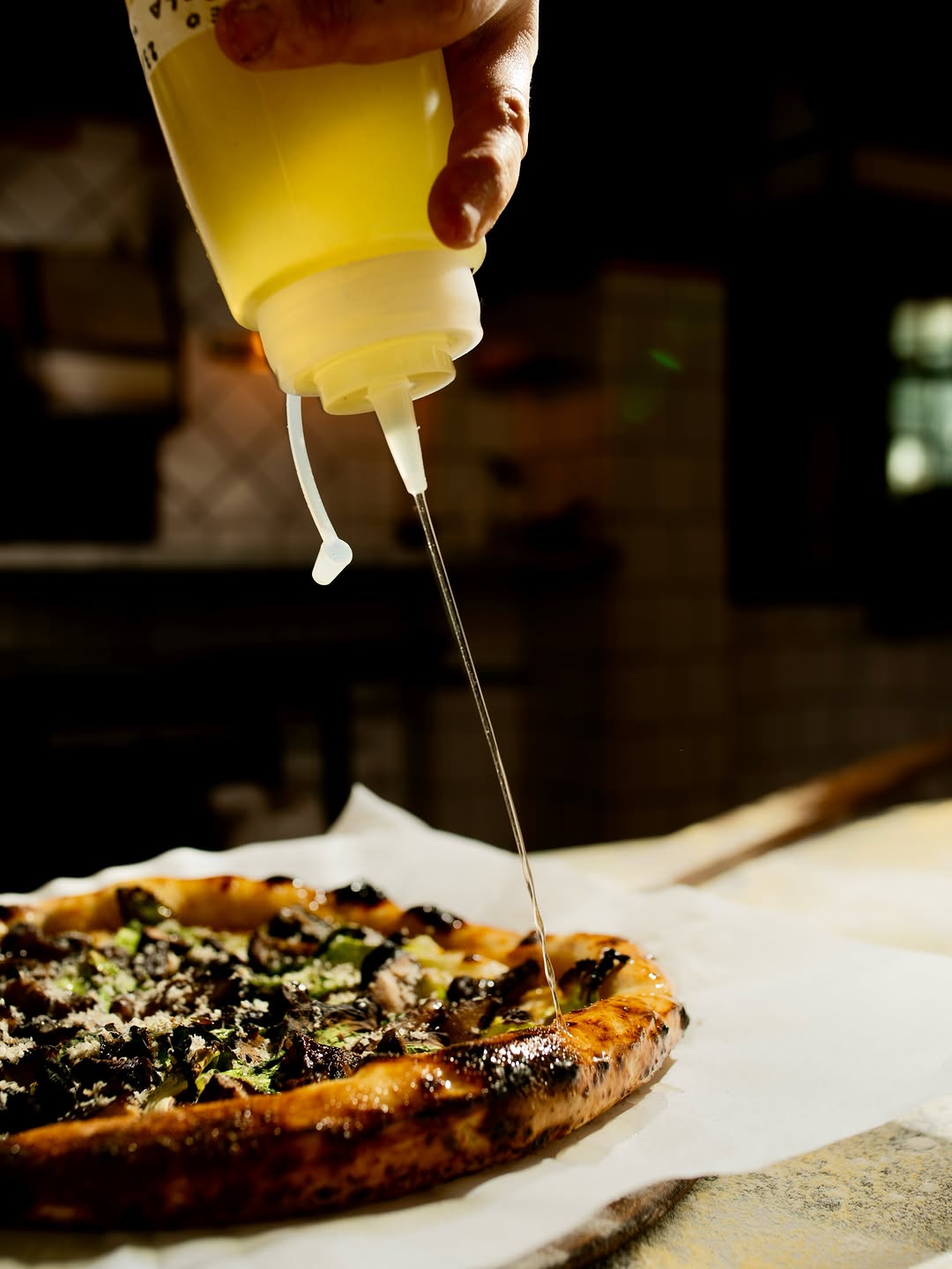 Pizza do Forno da Saudade recebendo fio de azeite na saída do forno